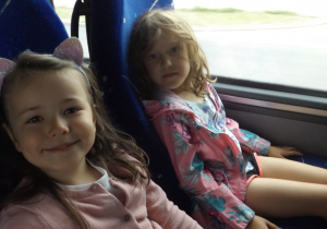 dwie dziewczynki siedzą obok siebie w autokarze jadąc na wycieczkę